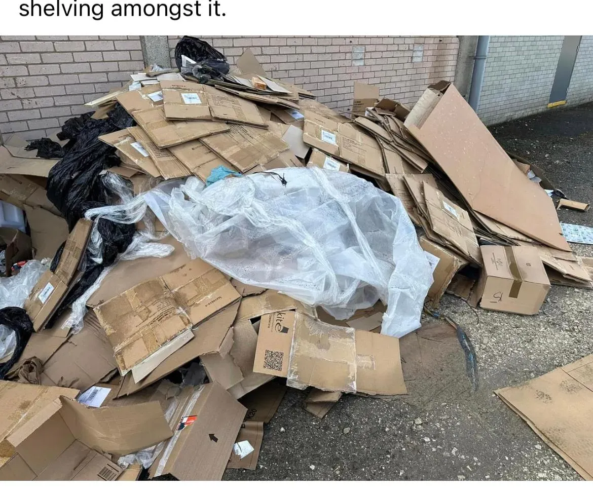 Pile of commercial packaging waste, including cardboard, plastic, and bags, awaiting clearance.